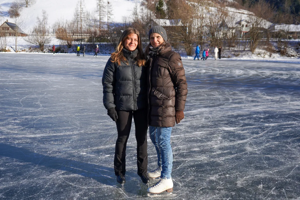 Man sieht zwei Frauen auf einem Eisfeld. 